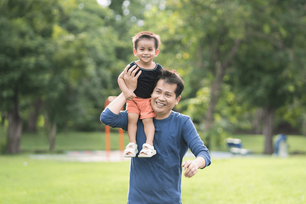 Asian father running in the park with his little toddler son sitting on his shoulder by kwanruanp

